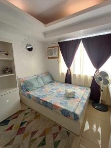 1 dormitorio con 1 cama y ventana con ventilador en Avida Tower 1 L21 staycation rm1002, en Iloilo City