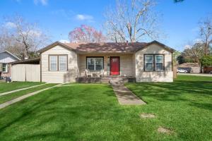 a house with a red door on a green yard at 3 bedroom 1 bath WiFi Large back yard with BBQ pit in Baytown