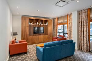 a living room with two blue couches and a tv at Hôtel 2170 Lincoln Downtown Montreal in Montreal