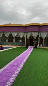 a large building with purple and green grass at Chalet LV in Hafr Al Baten