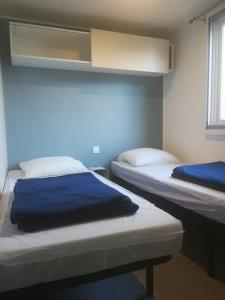 two beds in a room with blue walls at Camping de Lanven in Plomeur
