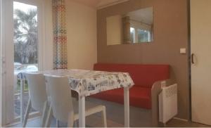 a dining room with a table and a red couch at Camping de Lanven in Plomeur