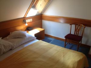 a bedroom with a bed and a chair and a window at Hotel Apart Hotel in Hévíz