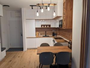 a kitchen with white cabinets and a wooden table and chairs at Mountain Oasis Bjelasnica in Bjelašnica