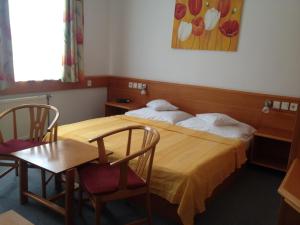 Hotel Apart Hotel في هفيز: غرفة فندقية بسرير وطاولة وكراسي