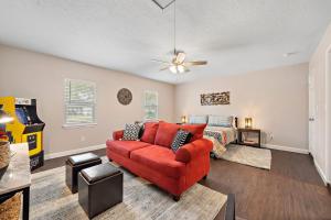 a living room with a red couch and a bed at with Arcade and Covered Patio Sleep 9 in this 4 Bedroom 2 Bath Home 5 star host Deer Park TX in Deer Park