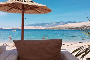 a chair under an umbrella on a beach at City Pag Apartment in Pag