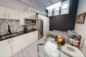 a kitchen with white cabinets and a sink and a bed at Studio in the heart of downtown in Ottawa