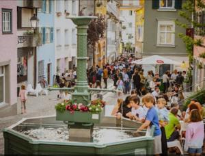 a fountain in the middle of a street with a crowd of people at OH 5 in Bregenz