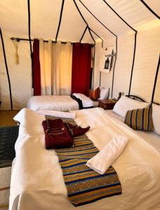 a room with three beds with towels on them at Authentic Desert Luxury Camp in Merzouga