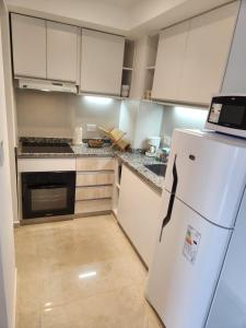 uma cozinha com armários brancos e um frigorífico branco em Costanera Vista em Posadas