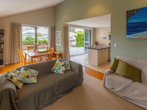 a living room with a couch and a table and a kitchen at Waihi Wonder - Waihi Holiday Home in Waihi Beach