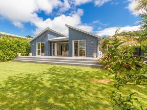 a blue house with a lawn in front of it at Waihi Wonder - Waihi Holiday Home in Waihi Beach