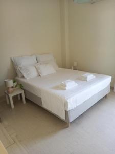 1 dormitorio con 1 cama grande con sábanas y almohadas blancas en ΝΑRIKA, en Kamena Vourla
