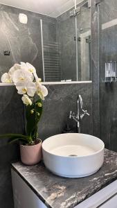 a bathroom with a white sink and flowers on a counter at Baltic Gdansk OLD TOWN in Gdańsk