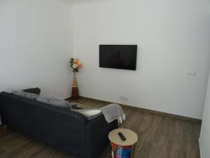 sala de estar con sofá negro y TV en Casa do Poço, en Vila Real de Santo António