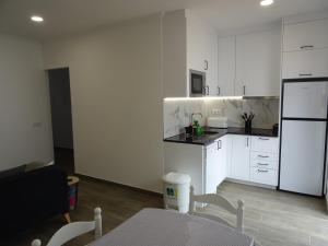 uma cozinha com armários brancos, uma mesa e um frigorífico em Casa do Poço em Vila Real de Santo António