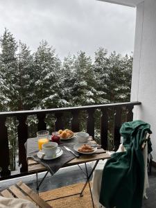 a breakfast table on a balcony with a view of trees at Apartamento LOS CORZOS - LA PINILLA in Cerezo de Arriba