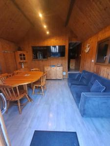 a living room with a table and a blue couch at chalet 6 personnes avec piscine in Cabourg