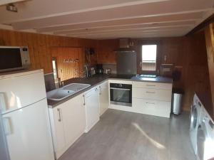 a large kitchen with white cabinets and a window at chalet 6 personnes avec piscine in Cabourg