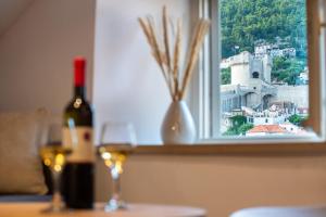 una bottiglia di vino e due bicchieri su un tavolo con finestra di Shee-Lu Suite 2 a Dubrovnik