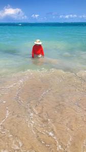 a man in the ocean wearing a hat at Carneiros Camping Hostel in Tamandaré