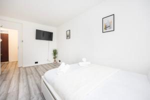 a white bedroom with a bed and a flat screen tv at Modern 2 BR Near Brixton Station in London