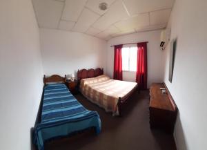 a room with two beds and a table and a window at Departamentos Luci in Embalse