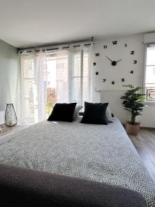 a bedroom with a large bed with a clock on the wall at *NEW* ALBA 6 pax Appart 8min Disney in Serris