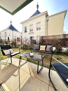 a patio with a couch and a table in front of a building at *NEW* ALBA 6 pax Appart 8min Disney in Serris