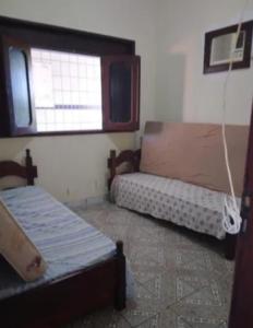 a small room with two beds and a window at Carneiros Camping Hostel in Tamandaré