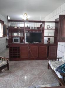 a living room with a flat screen tv and wooden cabinets at Carneiros Camping Hostel in Tamandaré