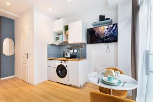 a kitchen with a washing machine and a table at Guestrust - Champeret Porte Maillot - Ternes in Paris