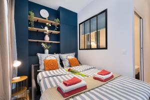 two beds in a bedroom with blue walls at Guestrust - Champeret Porte Maillot - Ternes in Paris