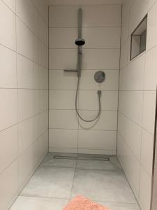 a shower with a shower head in a white tiled bathroom at FeWo Weiß Mauchen in Schliengen