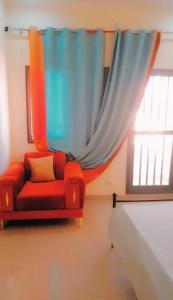 a red couch sitting in a room with a window at Salam in Thiès