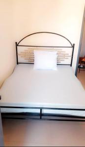 Cama blanca con cabecero de metal y almohada blanca en Salam, en Thiès