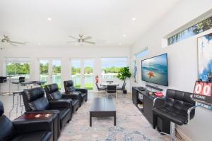 uma sala de estar com mobiliário de couro preto e uma televisão de ecrã plano em Summertime Suites #49 em West Bay
