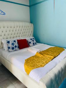 a large white bed with a yellow blanket on it at Budget Studio. Nakuru CBD. Wifi. Spacious. Ample Parking in Nakuru