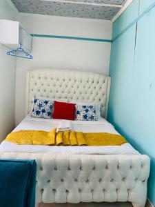 a bedroom with a white bed with blue and red pillows at Budget Studio. Nakuru CBD. Wifi. Spacious. Ample Parking in Nakuru