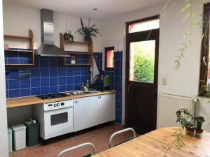 een keuken met een wit fornuis en blauwe tegels bij Cozy & Comfy House in Forest! in Brussel