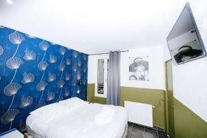 um quarto com uma cama e uma parede azul em Hotel De La Poste em Paris