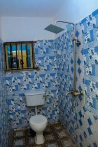 y baño de azulejos azules con aseo y ducha. en Rehoboth hotel, Apartment and Event services, en Suberu Oje