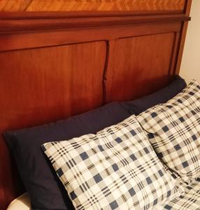 Cama con cabecero de madera y almohada en Gniazdo w Felicjanowie, en Uniejów