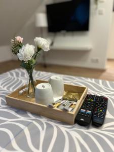 a tray with a remote control and a vase of flowers at Im Herzen von Rüsselsheim in Rüsselsheim