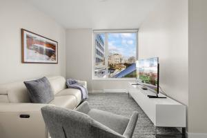 uma sala de estar com um sofá e uma televisão em Pristine & Modern Parliament View Condo, James Bay, Gym, Parking. em Victoria