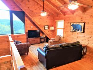 a living room with leather furniture in a log cabin at Brew with a View Lodge in Ducktown