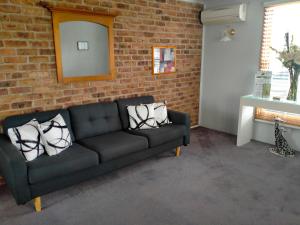 um sofá preto num quarto com uma parede de tijolos em Sandstock Motor Inn Armidale em Armidale