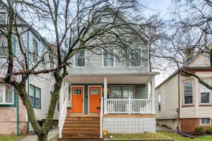 a white house with an orange door and stairs at Luxury Condo, Steps to Downtown Montclair and Train! in Montclair
