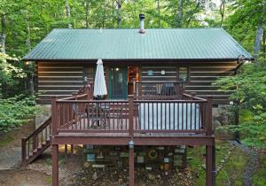 une cabane en rondins avec une terrasse et un parasol dans l'établissement Laurel Creek- Blue Ridge, à Blue Ridge